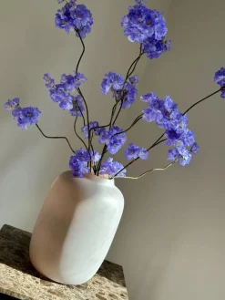 Beige vaas mat met blauw paars zijden bloesemtakken