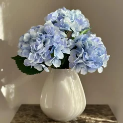 Beige vaas met blauwe kunst bloemen boeket